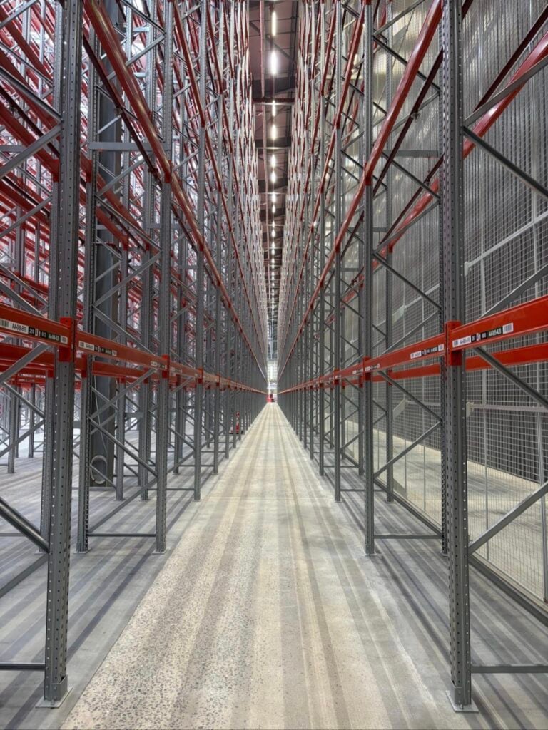 Narrow aisle high-bay pallet racking system in a large warehouse storage facility.